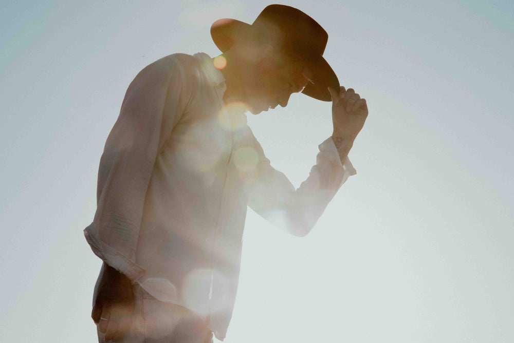 Man wearing fallen broken street black cowboy hat in the sunset