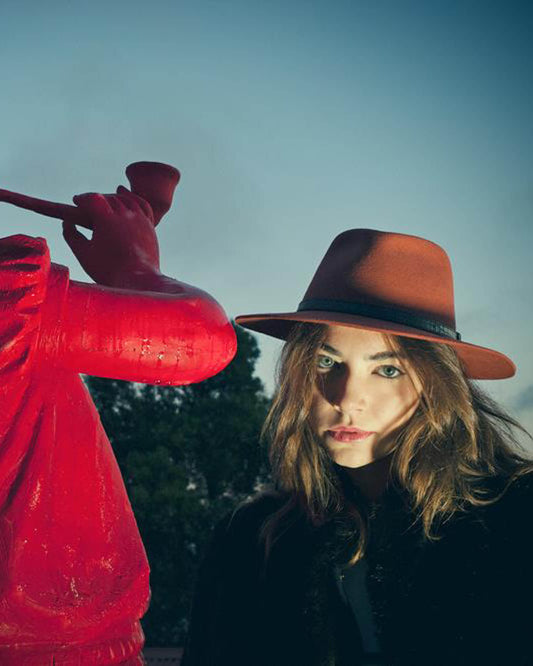 Model wearing The Dingo Felt Hat – Rust outdoors. Unisex wool felt fedora from FallenBROKENstreet featuring leather band and breathable cotton interior.