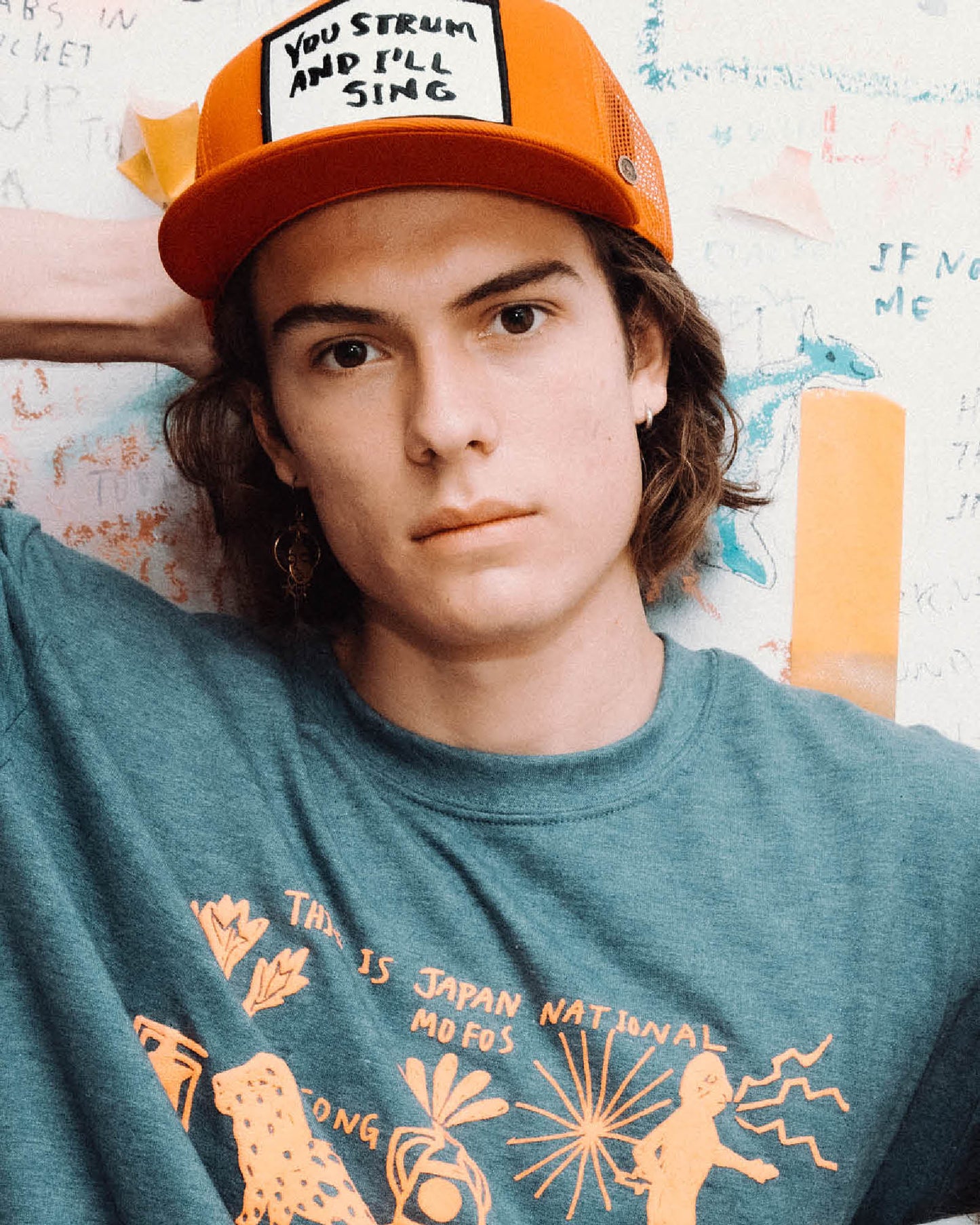 Model wearing red Marty Baptist x FallenBROKENstreet trucker cap with graphic t-shirt – lifestyle image