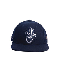 Front-facing view of the Marty Baptist x FallenBROKENstreet Miracle Eye Cap in navy. Features a wool felt structured build and embroidered Miracle Eye artwork on the crown. Designed as a limited edition release with only 50 units available in each size. A bold artist collaboration showcasing wearable street art.