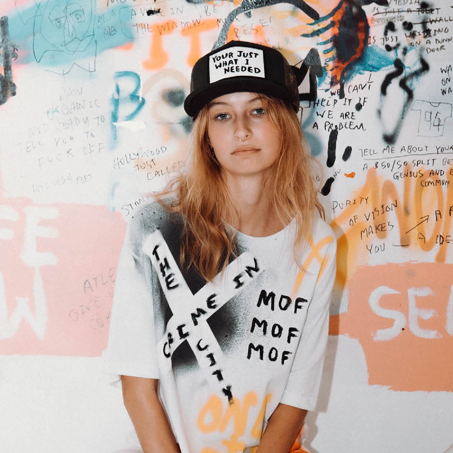 Model wearing black Marty Baptist trucker cap with graffiti wall background