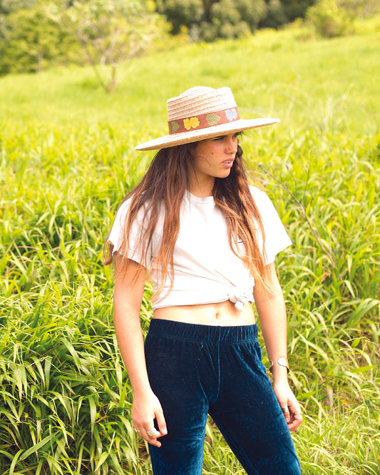 Woman wearing The Wanderer straw hat in a grassy field, styled with a white tee and navy pants – Fallenbrokenstreet.