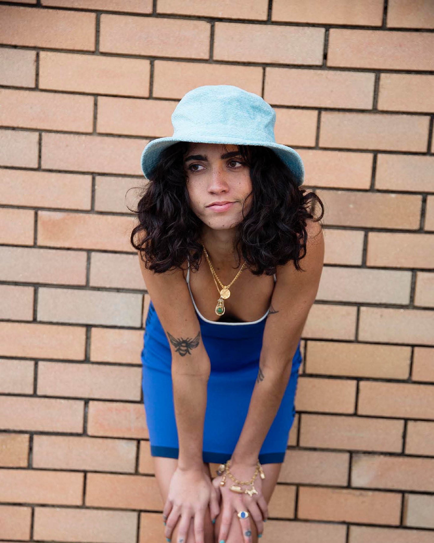 Model wearing Saturday Bucket Hat – Blue by FallenBROKENstreet. Cotton chenille bucket hat with wide brim, cotton inner band, and UPF 50+ sun protection. Styled in a blue slip dress, highlighting casual summer elegance.