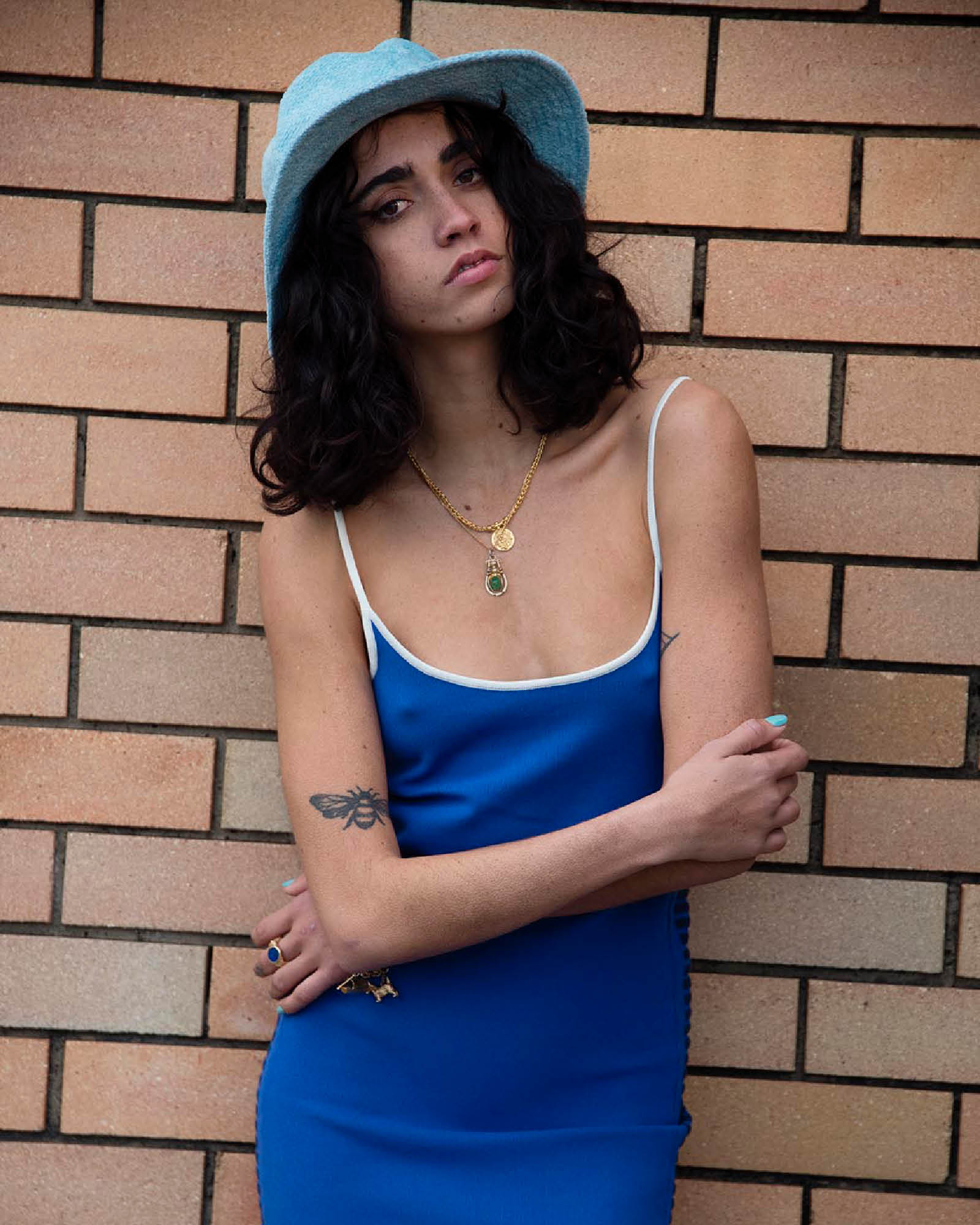 Portrait shot of model wearing the Saturday Bucket Hat – Blue. Lightweight cotton chenille with wide brim, breathable cotton inner band, and UPF 50+ rating. A bright unisex summer essential for festivals, beach days, and streetwear styling.