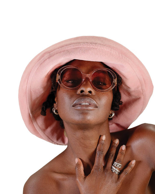 Woman wearing The Sunday pink foldable bucket hat from FallenBROKENstreet with rose sunglasses, styled for summer comfort and effortless cool.
