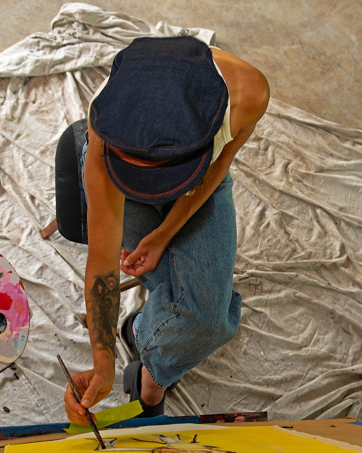 Model painting while wearing The Original Kyte Cap – Dark Indigo at the David Bromley Estate. Unisex denim cap with rope band and leather inner lining.