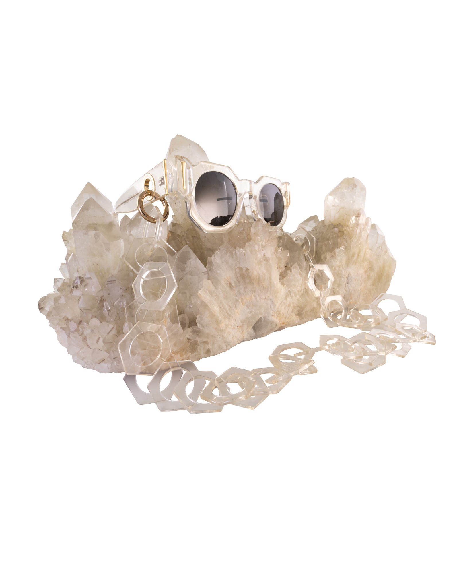 Product styling shot with The Cosmos sunglasses placed on quartz crystal, with a gold chain threaded through. Highlights chain compatibility and natural elements. Perfect for brand storytelling and visual merchandising.