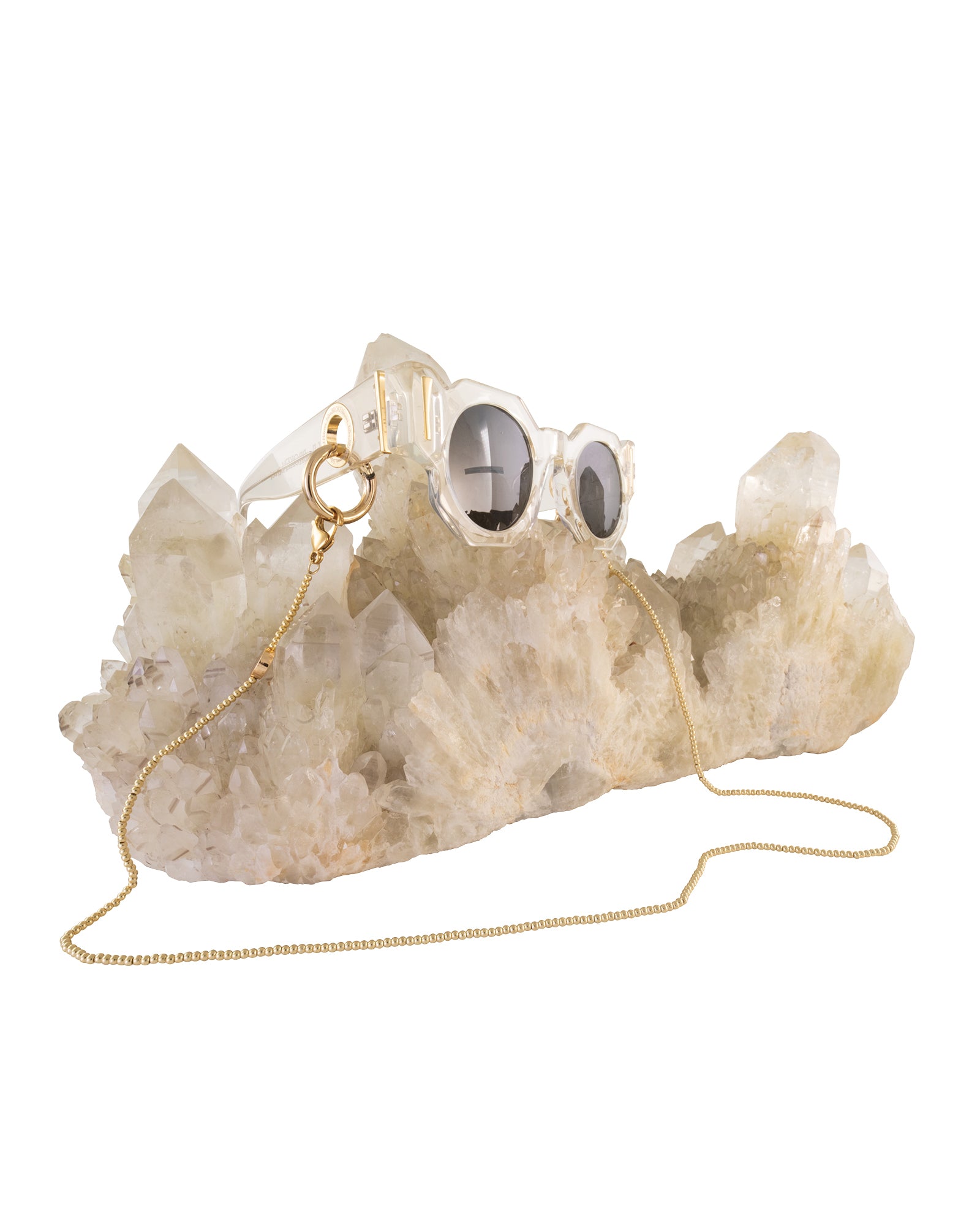Artful product image of The Cosmos – Skywalker/Black paired with gold Fallenbrokenstreet chain, resting on quartz crystal. Emphasises both chain compatibility and luxury presentation. Shopify-optimized to sell chains alongside frames.