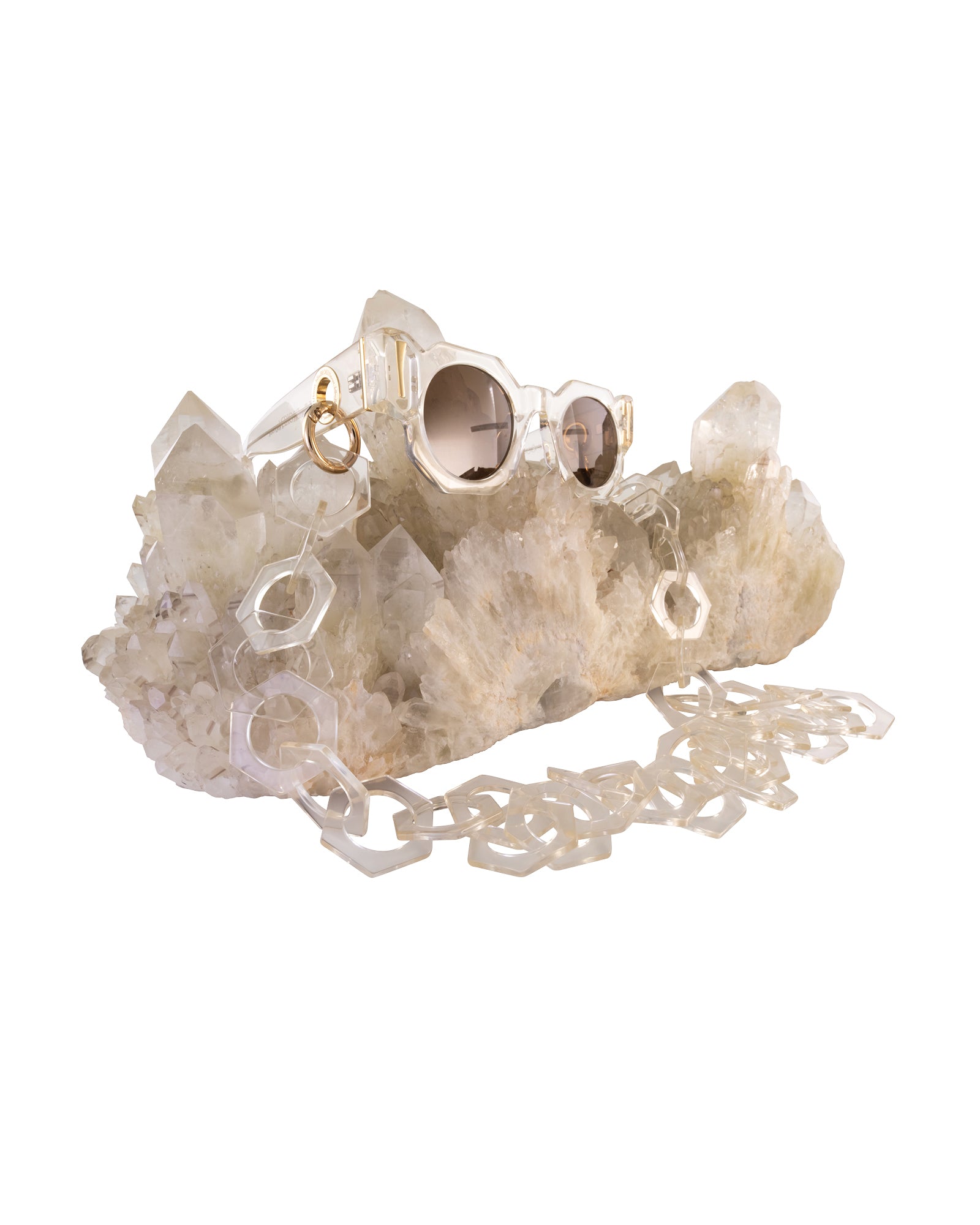 Alternate styled shot with clear acetate Cosmos sunglasses placed on quartz crystal. Amber lens glow softly, enhancing warmth and richness of tone. Perfect for product carousel or branding moments.