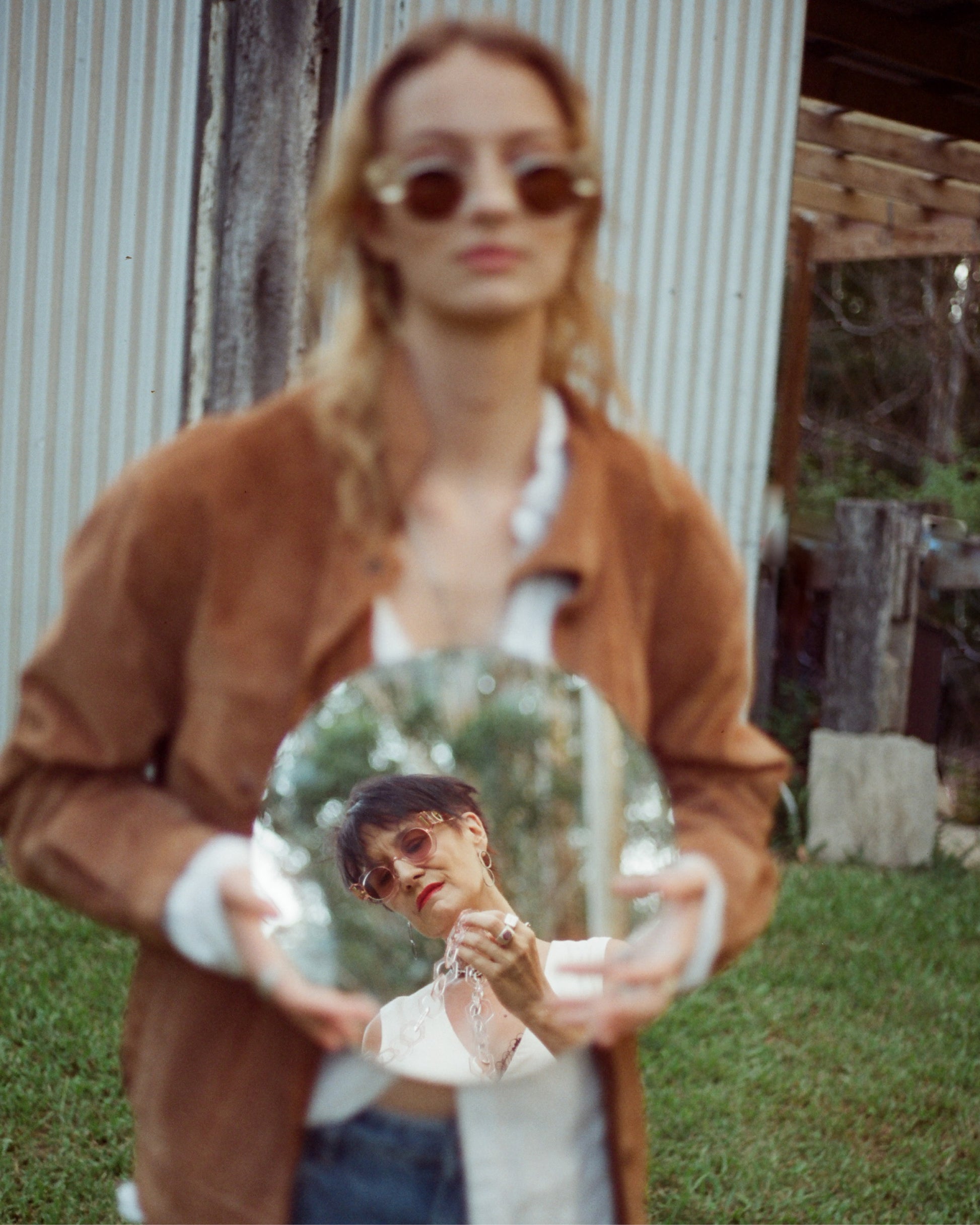 Fashion photo of model in The Cosmos – Skywalker/Amber sunglasses styled with shearling jacket and holding a ceramic sculpture. Fall tones complement amber lenses, delivering peak retro mood.