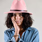 Woman wearing a pink hat and denim jacket against a plain background
