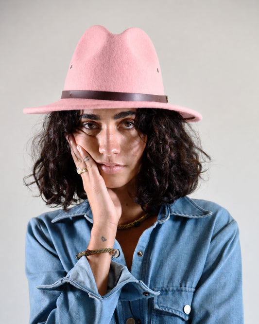Woman wearing a pink hat and denim jacket against a plain background