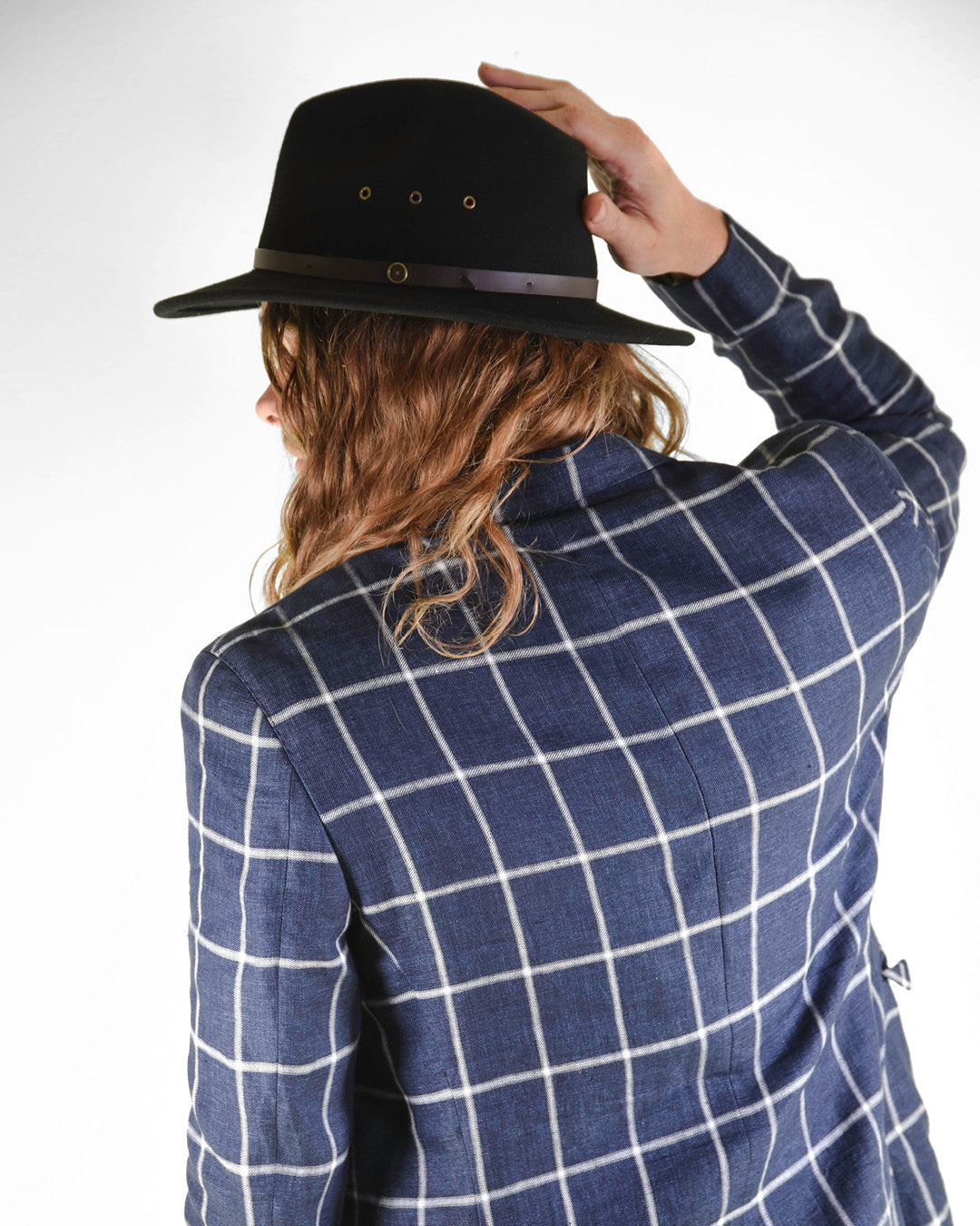 Person wearing a black hat and blue checkered jacket on a white background
