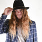 Person wearing a black hat and blue plaid jacket on a white background
