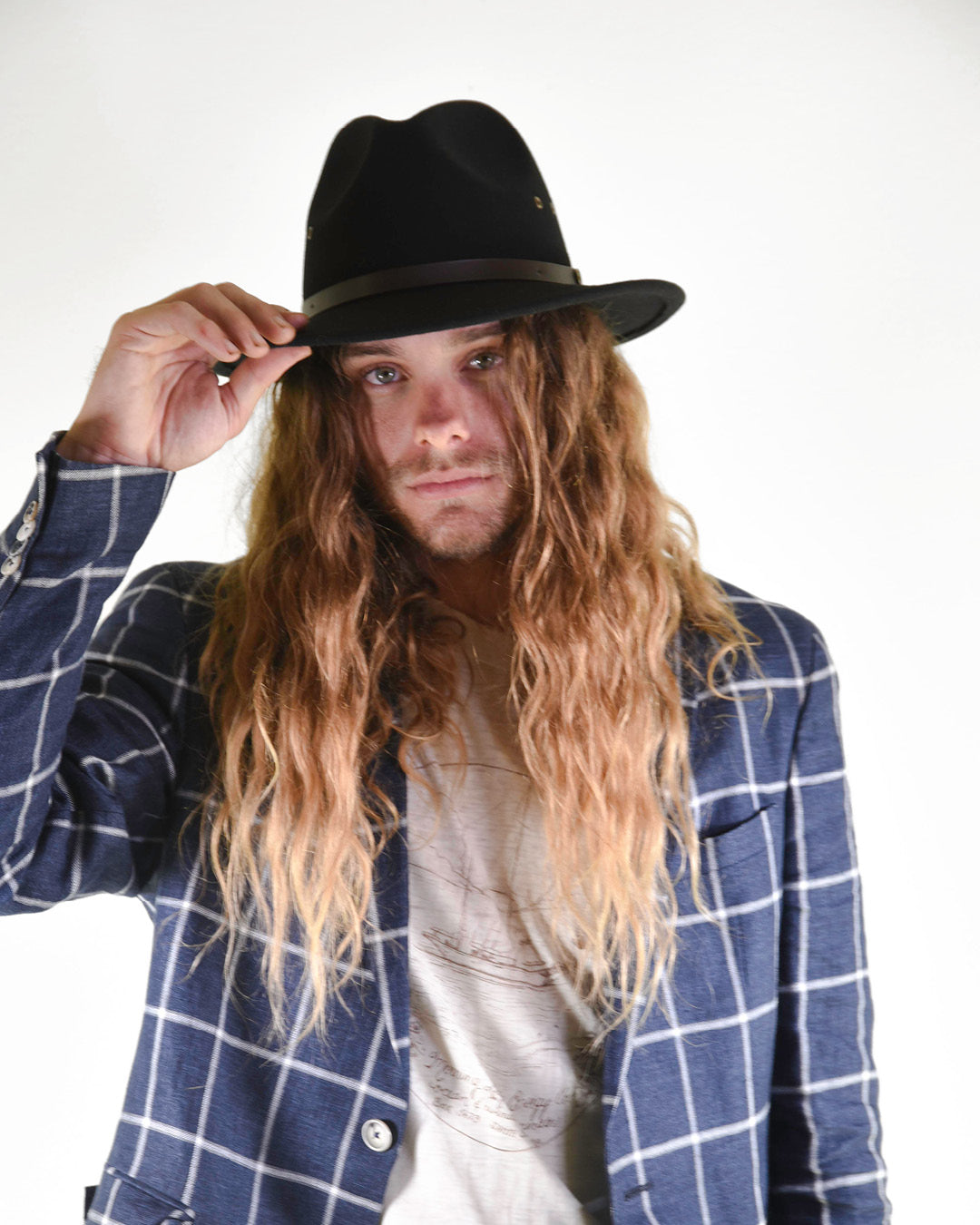 Person wearing a black hat and blue plaid jacket on a white background
