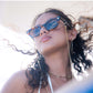 Dope Lemon sunglasses with beaded chain worn by model as wind blows hair on boat.
