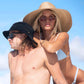 Two models lounging on a boat in swimwear and Dope Lemon sunglasses, ocean in background.