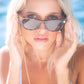 Model in light blue bikini adjusting Dope Lemon sunglasses with serious expression.