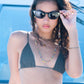 Model adjusting Dope Lemon sunglasses while wearing black bikini and beaded chain.