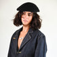 Front-facing shot of model wearing beret styled with open shirt, exuding relaxed French charm.


