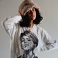 Model poses in profile with hands on hips while wearing The Cosmic Girl Bucket Hat in Tan Faux Fur. The image captures the depth of the crown and the soft curve of the brim, illustrating the hat’s warmth, comfort, and nostalgic aesthetic. A perfect unisex accessory for winter adventures or casual cosmic vibes.

