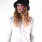 Person wearing a black hat and white shirt with red design on a white background