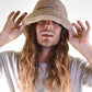 Person wearing a beige bucket hat with long hair against a white background