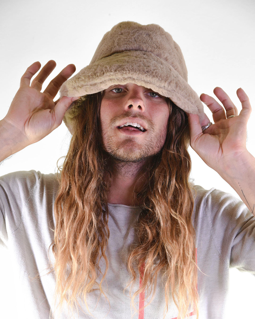 Person wearing a beige bucket hat with long hair against a white background