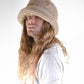 Person wearing a beige bucket hat with long hair on a white background