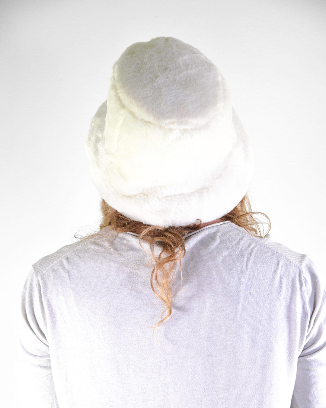 Person wearing a white knit hat on a plain background