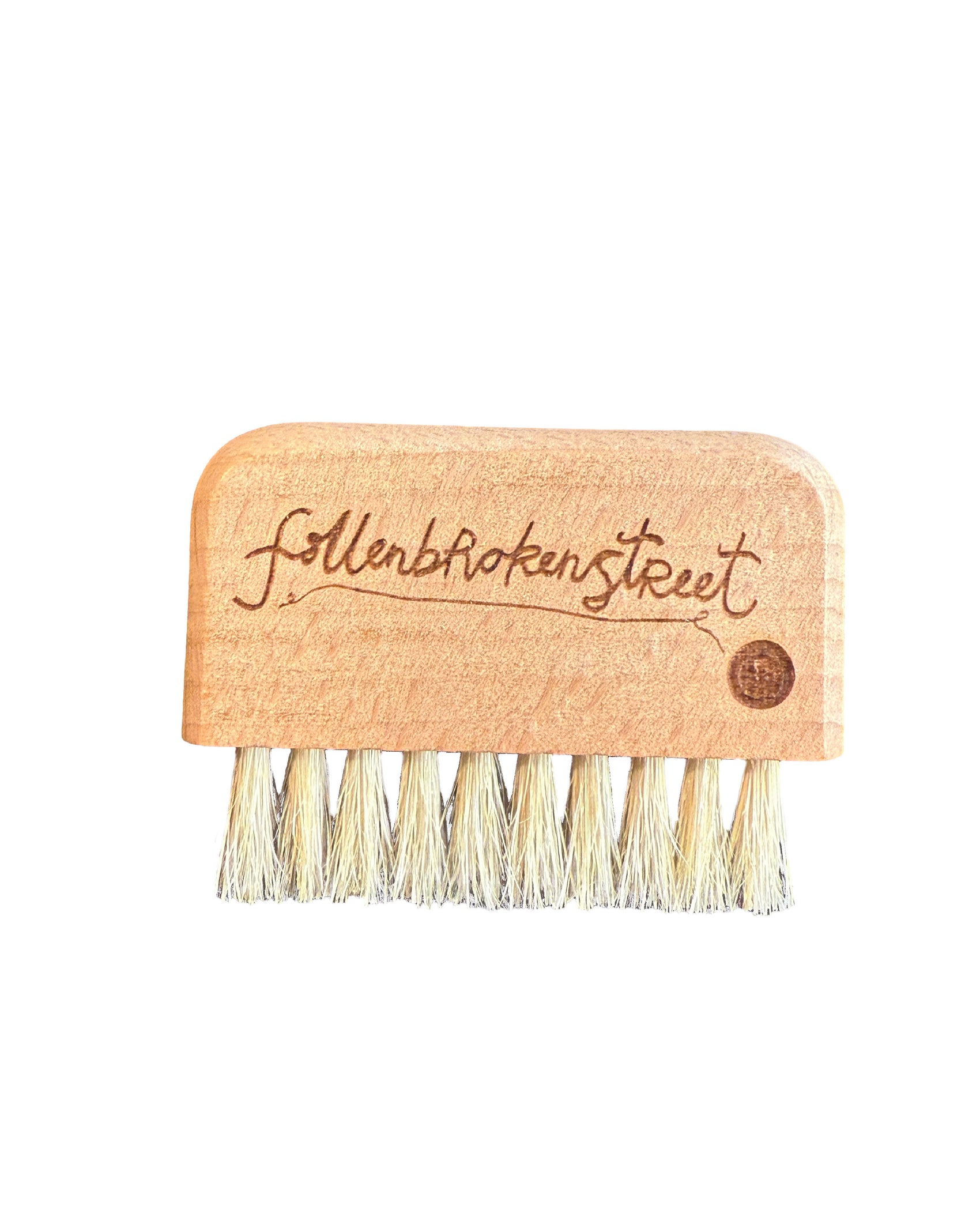 FallenBROKENstreet mini wooden hat brush photographed on a neutral surface, featuring the burnt logo detail on the handle, designed for keeping wool felt hats and straw hats clean. Compact travel size hat care accessory for festivals, everyday use, and hat lovers who value longevity.