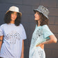 Models wearing the FlipSide Bucket Hat – Tan Reversible and Aztec Reversible by FallenBROKENstreet. The tan version offers a clean, minimalist look while the Aztec version shows a bold patterned side. Both cotton canvas hats feature a wide brim, lightweight design, and reversible construction, making them perfect for festivals, coastal adventures, and everyday summer wear.