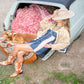 Woman sitting in a car trunk with a dog, wearing a blue dress and tan boots, surrounded by pink fabric and a blanket.Fallenbrokenstreet wide brim hat – side profile

