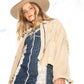 Woman wearing a beige fringe jacket, blue patterned dress, and beige hat against a white background Model wearing The Jose felt hat in natural light

