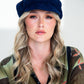 Woman wearing a navy blue cap with a plain background
