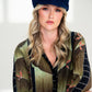 Woman wearing a patterned shirt and navy cap against a white background
