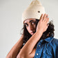 Side View on woman Beige Lucks Beanie in premium wool blend, ribbed knit design, unisex flexible fit.