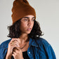Model wearing The Lucks Beanie in brown, styled with a denim jacket. FallenBROKENstreet wool blend beanie with ribbed knit texture, logo badge on fold, and relaxed fit. Designed for comfort and warmth, this unisex beanie is perfect for festival style, casual streetwear, or layering in cooler months.