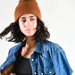 Model wearing The Lucks Beanie in brown, styled with a denim jacket. FallenBROKENstreet wool blend beanie with ribbed knit texture, logo badge on fold, and relaxed fit. Designed for comfort and warmth, this unisex beanie is perfect for festival style, casual streetwear, or layering in cooler months.