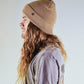 Tan Lucks Beanie by FallenBROKENstreet worn by model with long hair. Wool blend ribbed knit design with cuff and logo detail. A unisex beanie crafted for warmth and durability, offering versatile styling for festivals, casual wear, and outdoor living.