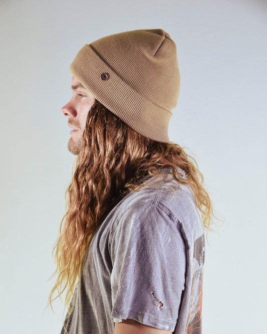 Tan Lucks Beanie by FallenBROKENstreet worn by model with long hair. Wool blend ribbed knit design with cuff and logo detail. A unisex beanie crafted for warmth and durability, offering versatile styling for festivals, casual wear, and outdoor living.