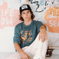 Model wearing black Marty Baptist Strum Cap with artistic wall background.