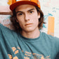 Model wearing red Marty Baptist x FallenBROKENstreet trucker cap with graphic t-shirt – lifestyle image

