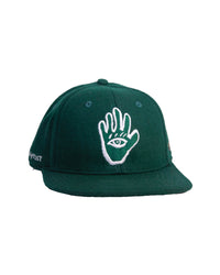 A green flat-brimmed wool felt cap with white embroidered artwork of a hand and an eye on the front.