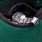 Close-up of the inside of the Miracle Eye green cap, revealing the hidden secret pocket with a watch tucked in. Designed for discreet storage and everyday practicality. Embodies creativity and craftsmanship, elevating the standard flat cap into functional fashion. Perfect for fashion-forward individuals or skate-culture styling.


