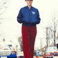 Model wearing the FallenBROKENstreet Oliver Cap – Red Tartan while walking through city streets. Bold plaid hat paired with retro blue jacket and red trousers for a timeless urban look.