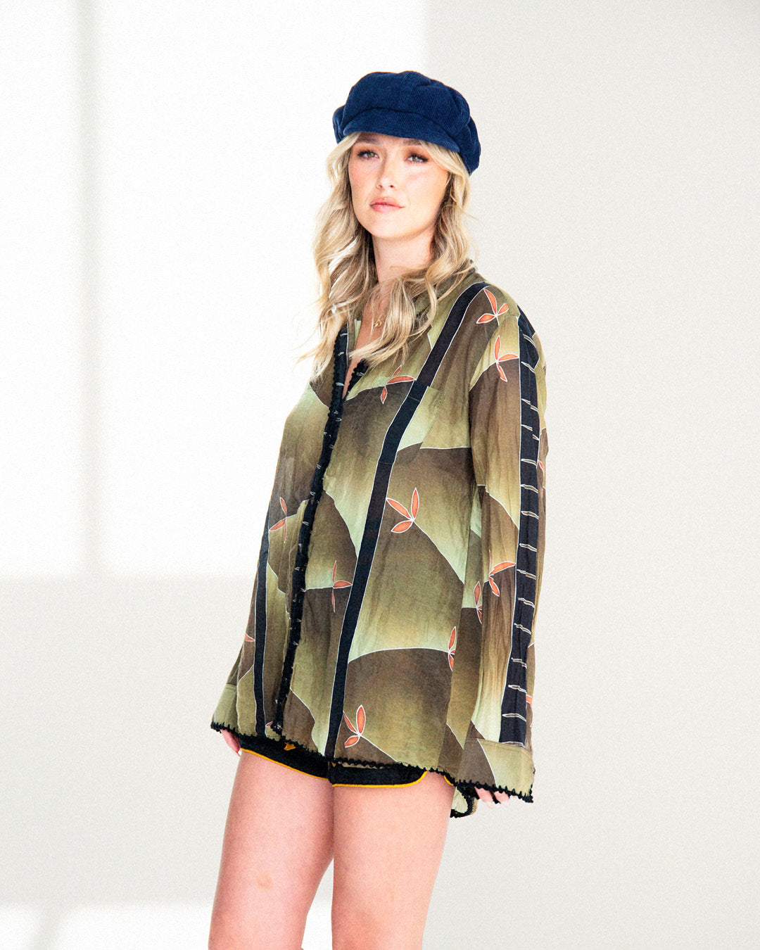 Woman wearing a patterned jacket and blue cap on a white background
