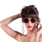 Model wearing THE ORBIT – Skywalker sunglasses with amber lenses and gold chain, styled with black outfit

