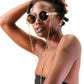 Female model wearing THE ORBIT – Skywalker round white sunglasses with amber lenses, posed in sunlight


