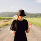 Model wearing black bucket hat on a country road

